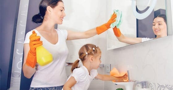 Mother and daughter cleaning a bathroom mirror and sink.