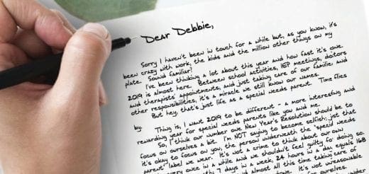 Hand writing "Dear Debbie," on a letter with a black pen.
