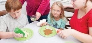 Children decorating cookies with frosting and sprinkles.