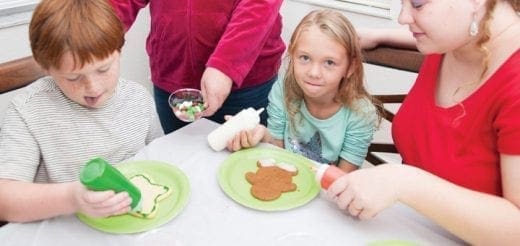 Children decorating cookies with frosting and sprinkles.