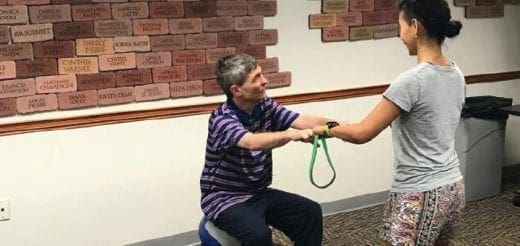 Man and woman using a resistance band in front of a brick wall