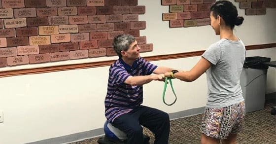 Man and woman perform a resistance band exercise.