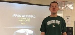 Jared Weinberg smiling in front of a projection screen.