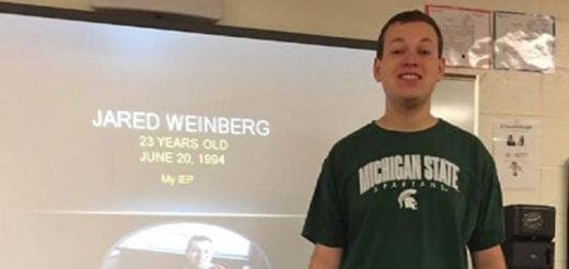 Jared Weinberg smiling in front of a projection screen.