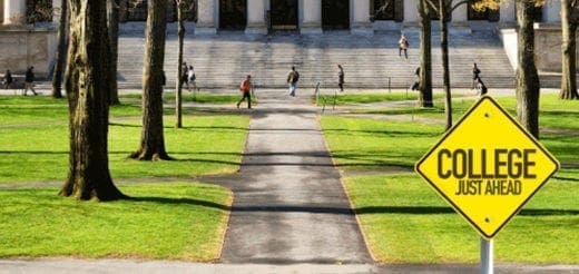 Yellow road sign reading College Just Ahead on a path leading to a university building.