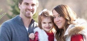 A family of three smiles at the camera.