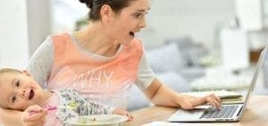 Woman typing on a laptop with a baby in her arms.