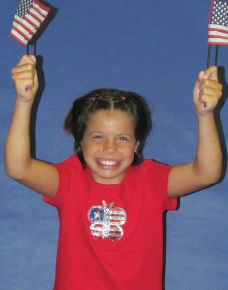 Gabrielle Ioffredo holding two American flags and smiling.