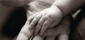Small infant hand resting gently on an adult palm.
