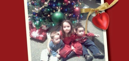 Three children sit near a Christmas tree with gifts.