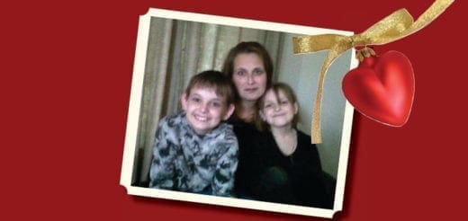 Ronan with two children in a framed photo with a red heart ornament.