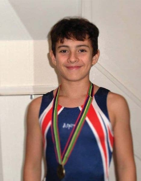 Young boy in a gymnastics leotard wearing a medal