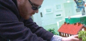 Matthew Shifrin examining a Lego house with greenery.