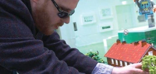 Matthew Shifrin examining a Lego house with greenery.