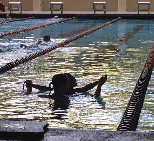 A swimmer in a pool reaches forward to swim.