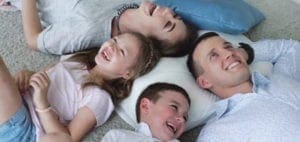 A family of four lies on the floor laughing.
