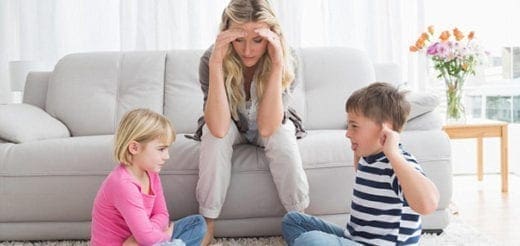 Mother with her head in her hands as two children argue in front of her