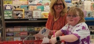 Two people stand in front of a display of greeting cards.