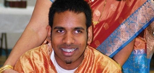 A man in an orange garment smiles at the camera.