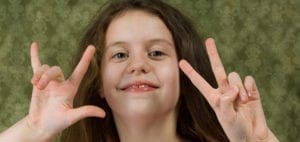 A girl makes ASL signs for "I love you" with her hands.