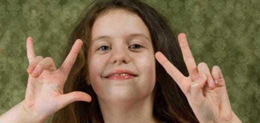 A girl makes ASL signs for "I love you" with her hands.
