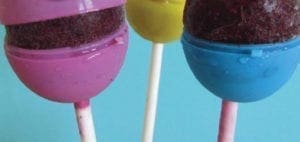 Three colorful egg-sicles on sticks against a blue background.