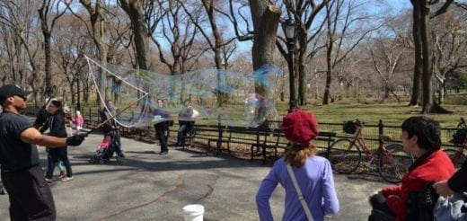 People blowing large bubbles in a park