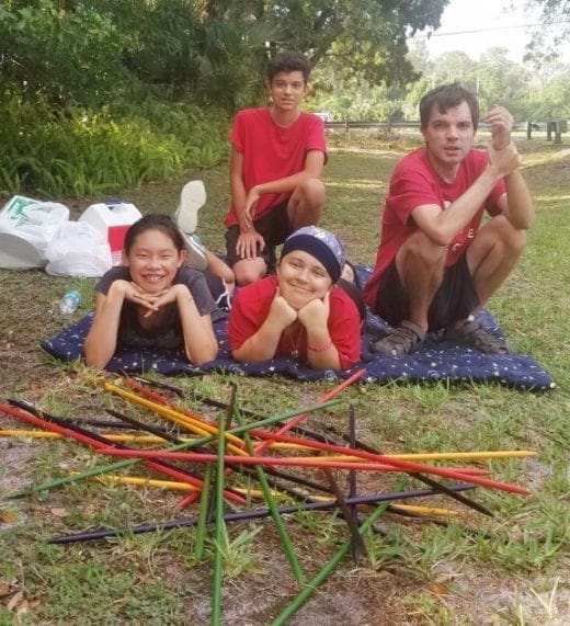 The Foster Family poses for a picture after playing a game of jumbo pick-up sticks outdoors.