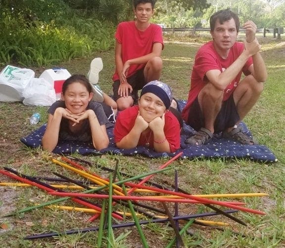 The Foster Family poses for a picture after playing a game of jumbo pick-up sticks outdoors.