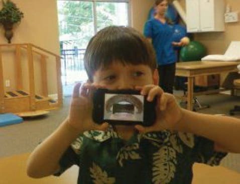 Boy holding a smartphone up to his face, looking at the screen.