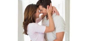 Couple embracing with their foreheads touching in an intimate moment at home.
