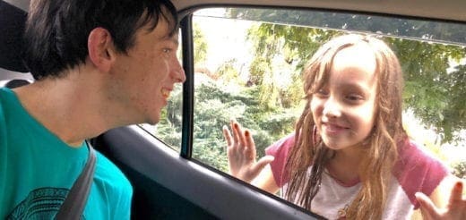 Parent in a car looking at a child waving through the window.