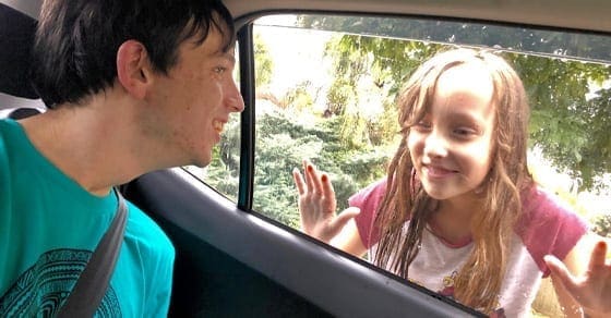 Man in car looks at a smiling young girl outside the window.
