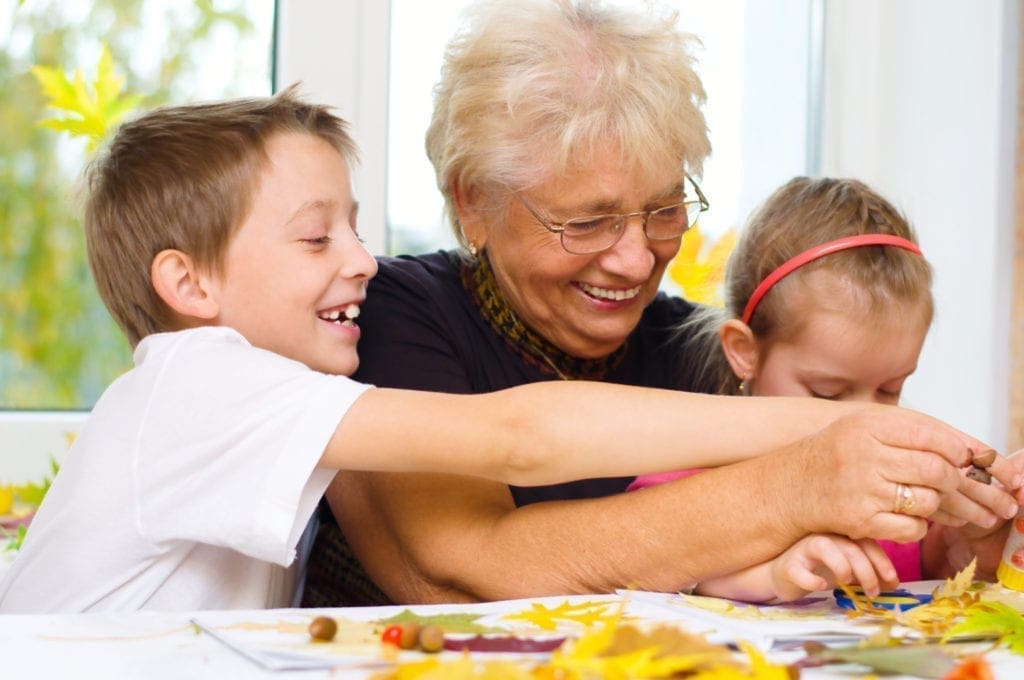 Woman with two children doing arts and crafts at a table.