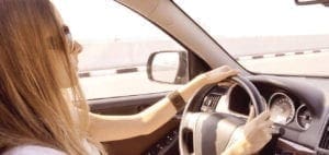 Woman with long blonde hair drives a car.