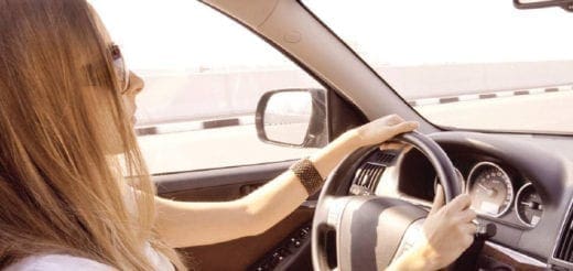 Woman with long blonde hair drives a car.