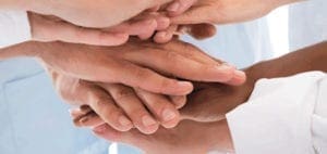 Several hands stacked on top of each other, symbolizing teamwork.