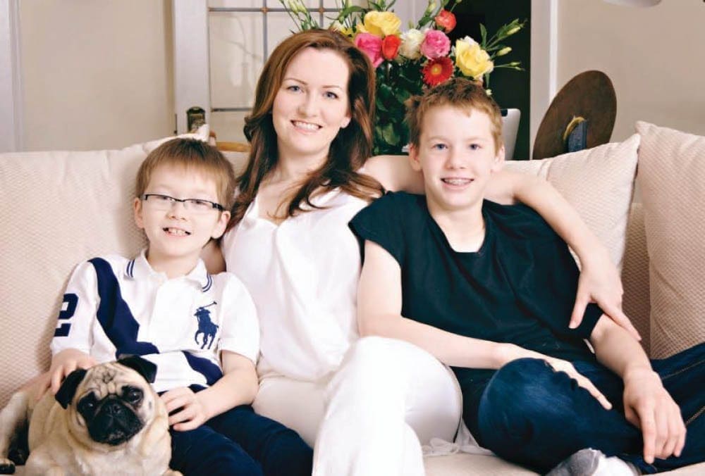 Janet with her sons Harrison and Taylor, and a pug, on a sofa.
