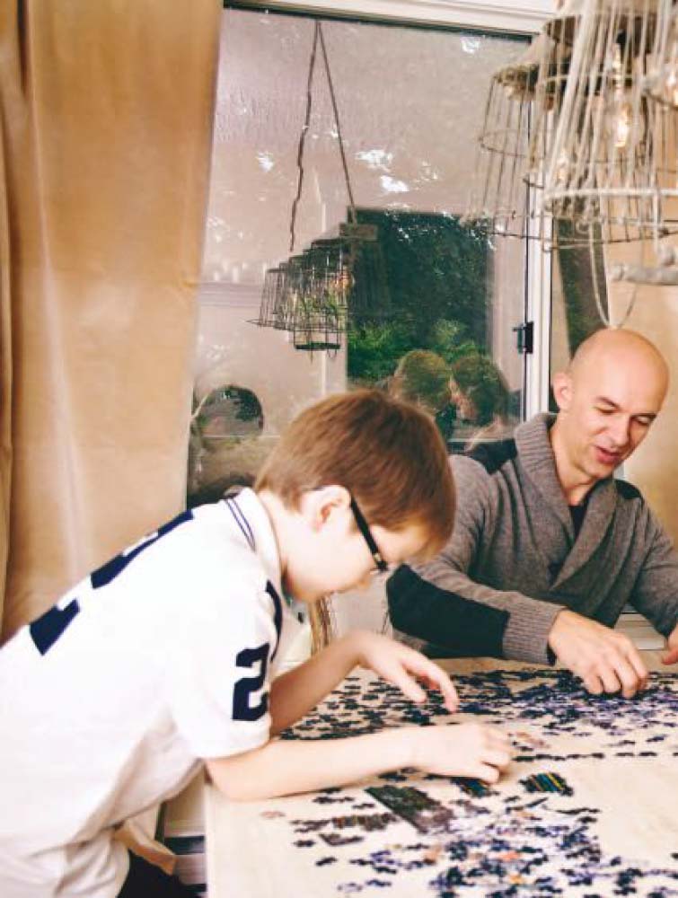 Harrison and an adult work on a puzzle at a table.