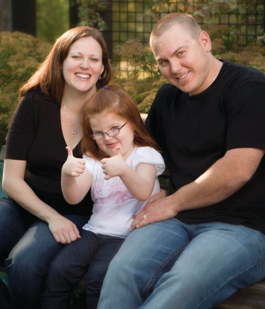 Kylie with her parents, giving a thumbs-up