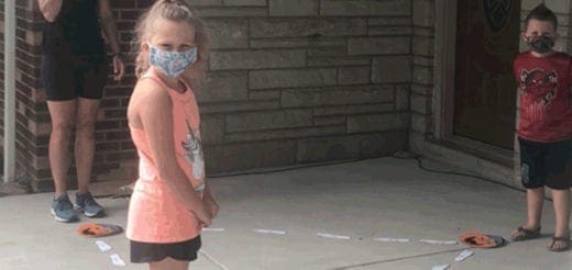 Children practice social distancing using pumpkin plates on a sidewalk.