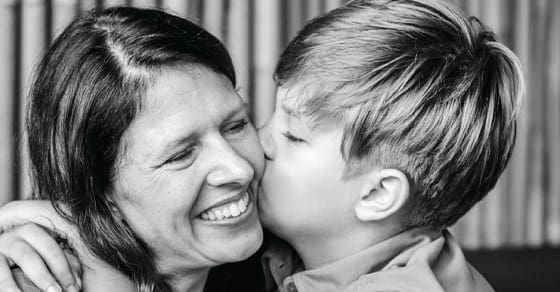 A boy kisses a woman on the cheek.