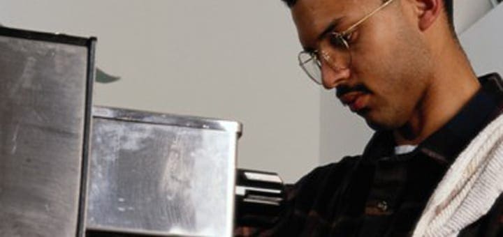 Man with mustache and glasses looking down.