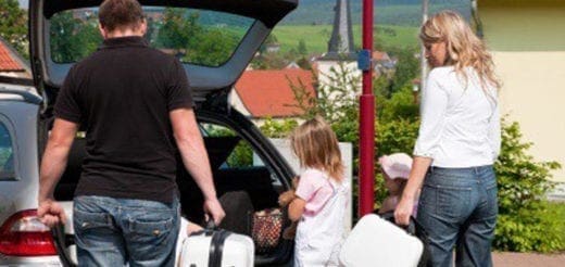 Family loading luggage into a car for a trip.