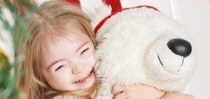 Young girl with Down syndrome hugging a stuffed animal.