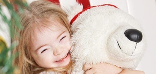 Young girl with Down syndrome hugging a stuffed animal.