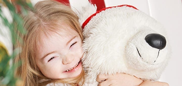 Young girl with Down syndrome hugging a stuffed animal.