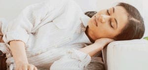 Woman resting her head on a couch cushion.