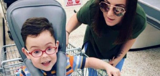 Child in shopping cart with red glasses and a woman in a green shirt.