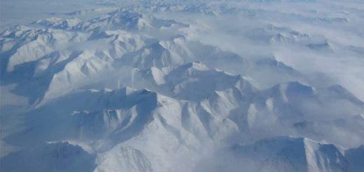 Snow-covered Alaskan mountains shrouded in mist.